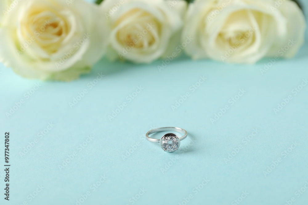 Beautiful ring with gemstone and flowers on light blue background Beautiful ring with gemstone and flowers on light blue background