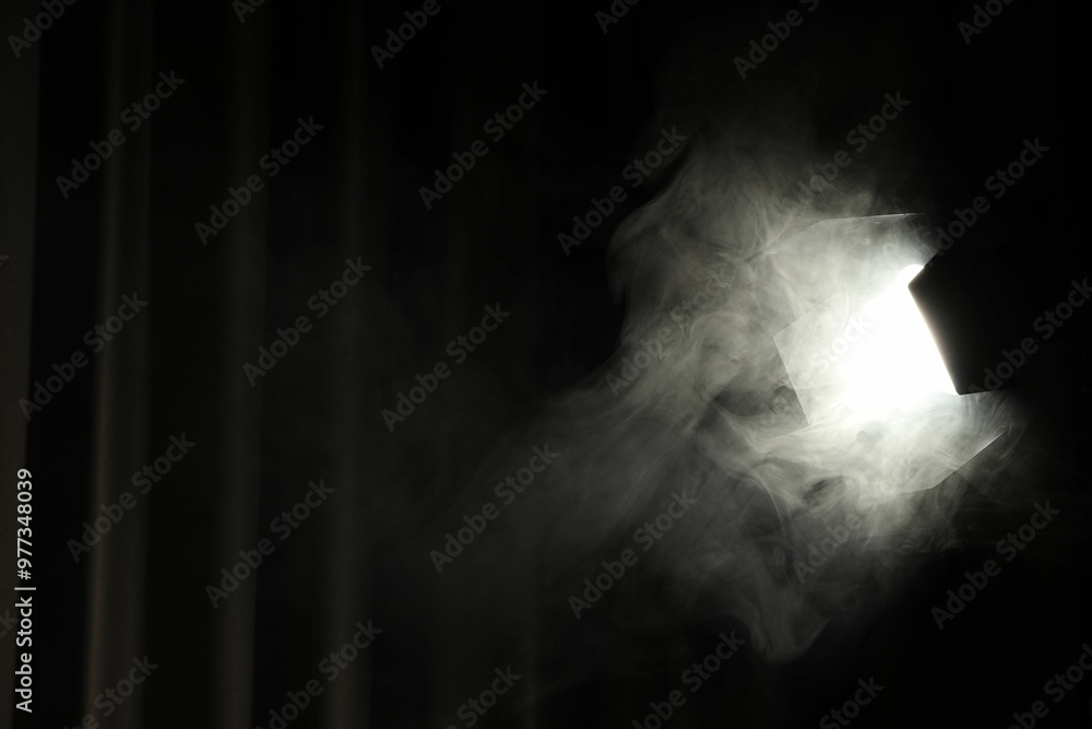 Professional spotlight and smoke against curtain in darkness. Space for text Professional spotlight and smoke against curtain in darkness. Space for text