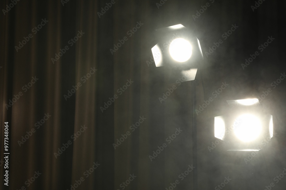 Professional spotlights and smoke against curtain. Space for text Professional spotlights and smoke against curtain. Space for text