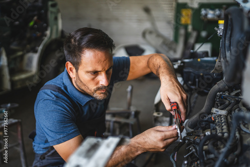 Car mechanic working on a car engine in a workshop with tools visible