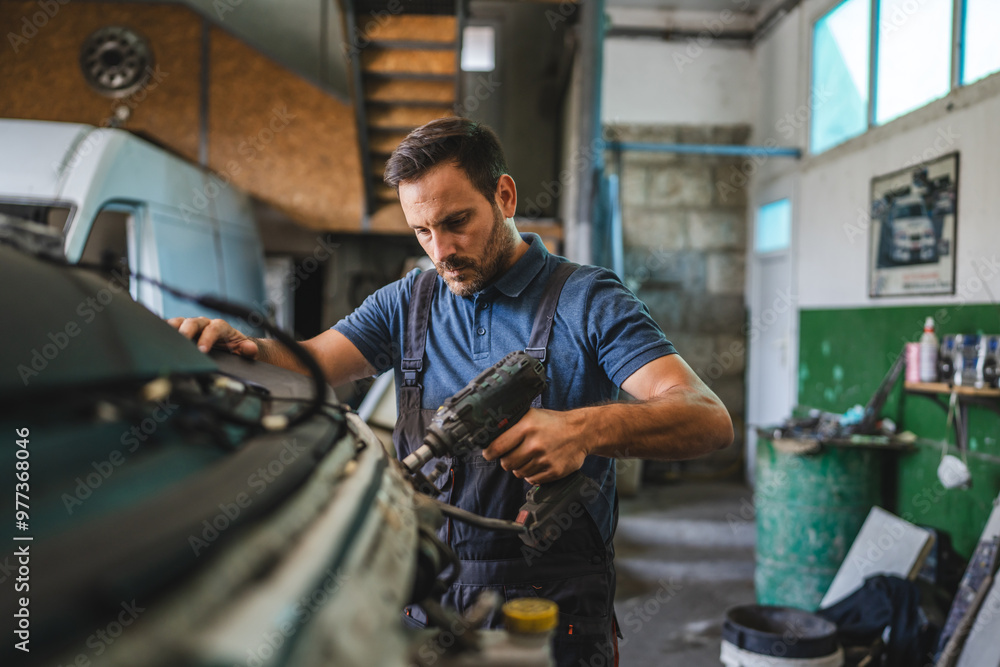 Car mechanic work on vehicle with drill tool in repair garage shop Car mechanic work on vehicle with drill tool in repair garage shop