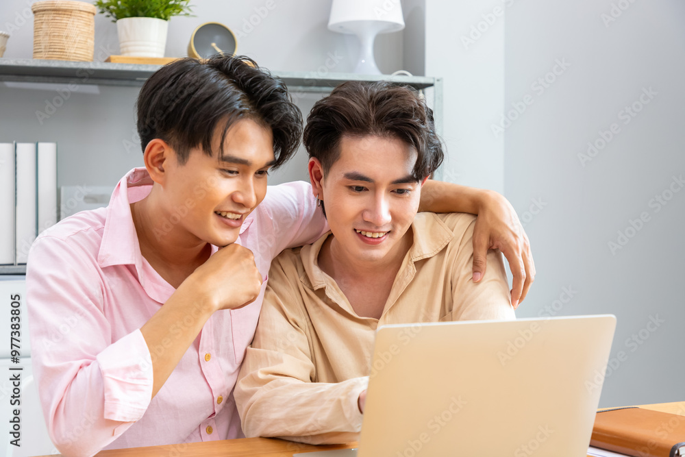 Two Asian men gay couple smiling and using laptop together in modern home office Two Asian men gay couple smiling and using laptop together in modern home office