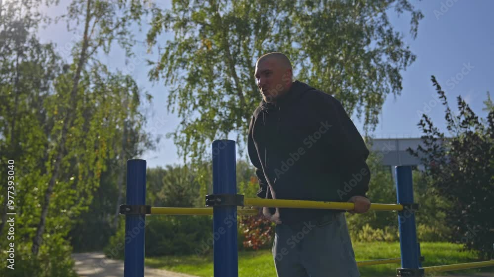 A bald man trains on a street simulator in a park on a sunny day. A bald man trains on a street simulator in a park on a sunny day.