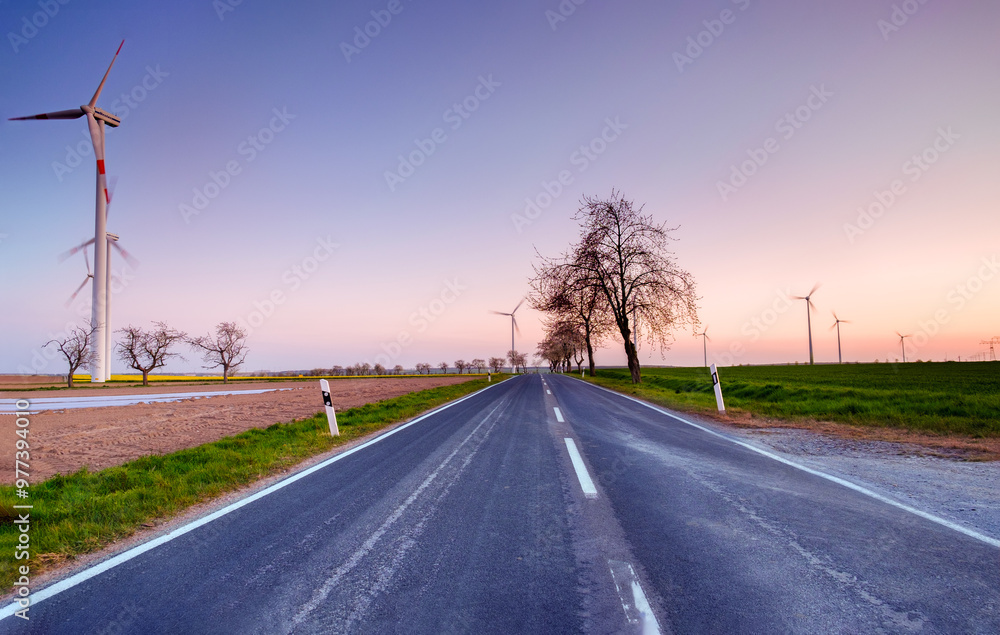 Fototapeta premium Empty Road at Sunset with Wind Turbines in the Distance