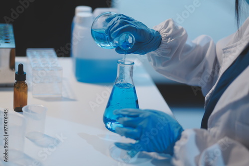 Group of dedicated scientist conduct chemical experiment in medical laboratory, carefully drop precise amount of liquid from pipette into test tube for vaccine drug or antibiotic development. Neoteric