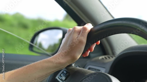 Close up camera shot of woman hands holding the cars steering wheel. Caucasian female drives the car. Freckles on woman's hand.