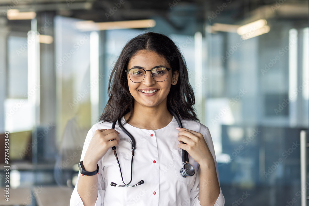 Portrait of young hispanic female doctor inside office, clinic worker close up smiling and looking at camera wearing white medical coat with stethoscope Portrait of young hispanic female doctor inside office, clinic worker close up smiling and looking at camera wearing white medical coat with stethoscope