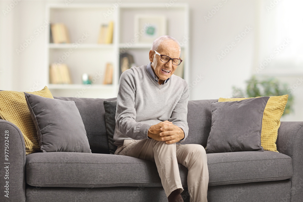Elderly man with pain in the knee sitting on a sofa Elderly man with pain in the knee sitting on a sofa