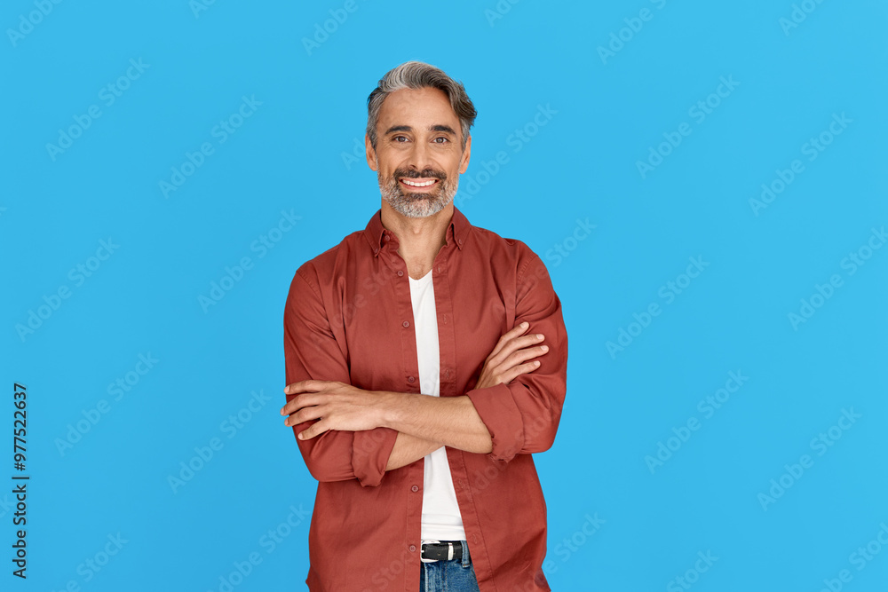 Happy mature man in his forties wearing casual shirt standing isolated on blue background. Smiling middle aged professional businessman looking at camera with arms crossed, portrait. Happy mature man in his forties wearing casual shirt standing isolated on blue background. Smiling middle aged professional businessman looking at camera with arms crossed, portrait.