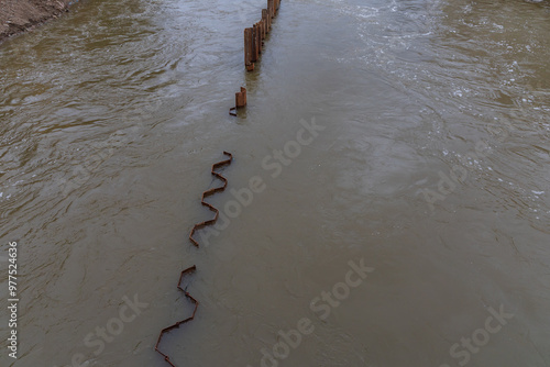 Svratka river in the city of Brno on Porici Street. Iron piles in the water.