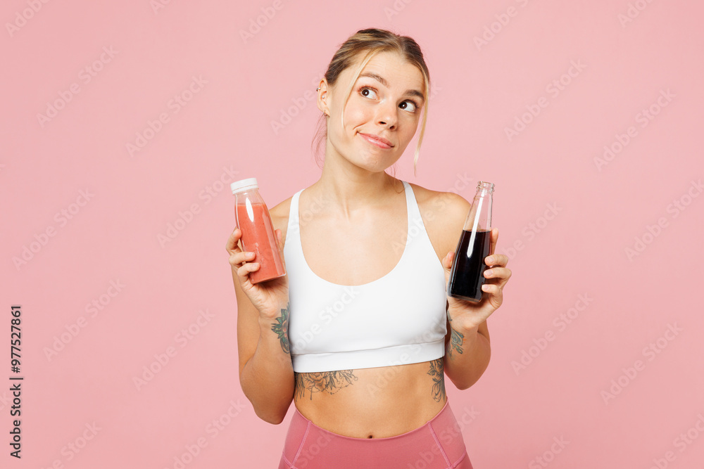 Young minded woman wears white top casual clothes hold choose between smoothie juice and soda pop isolated on plain pastel pink background. Proper nutrition healthy fast food unhealthy choice concept. Young minded woman wears white top casual clothes hold choose between smoothie juice and soda pop isolated on plain pastel pink background. Proper nutrition healthy fast food unhealthy choice concept.