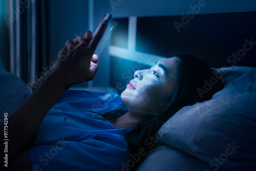 Asian female scanning face ID to unlock door security with facial recognition technology for identification, with graphical technology illustration. Playing with smartphone before going to bed. photo