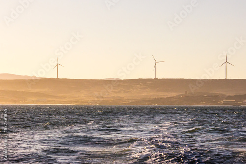 Wind turbines among the dunes of the Namib desert, along the coast in Namibia at dawn. photo