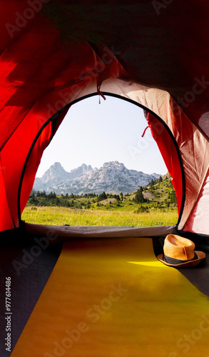 A beautiful view from the tent of a green meadow with rocky mountain peaks in the background