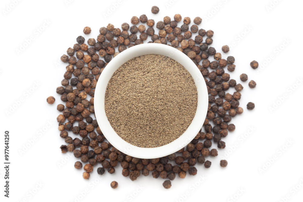 A bowl of Organic Black pepper (Piper nigrum) powder, placed over a heap of whole Black pepper. Isolated on a white background. A bowl of Organic Black pepper (Piper nigrum) powder, placed over a heap of whole Black pepper. Isolated on a white background.