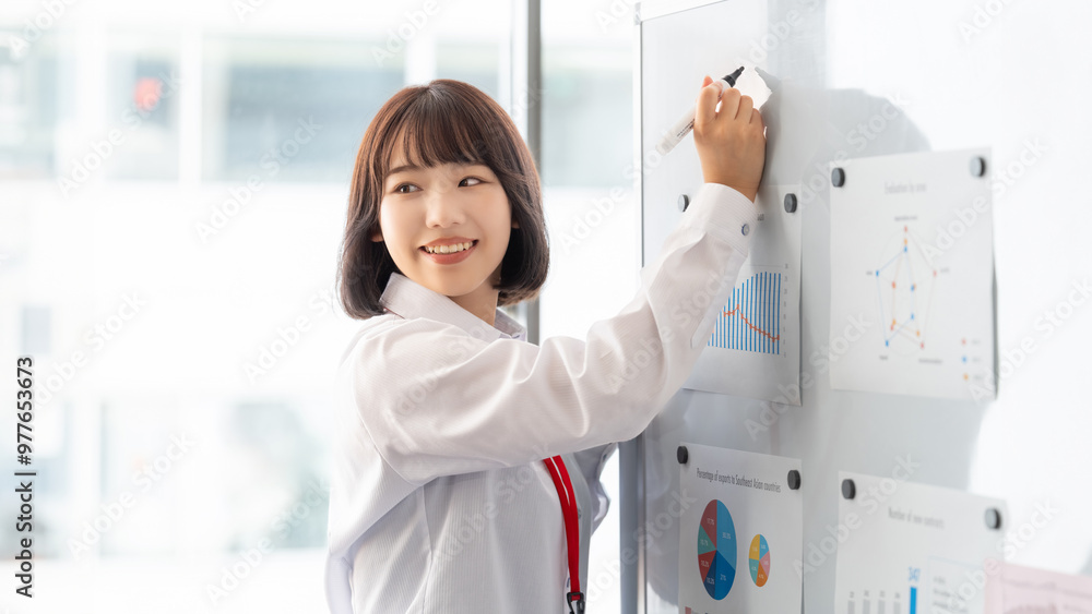 ホワイトボードを使ってプレゼンをする若いビジネスウーマン ホワイトボードを使ってプレゼンをする若いビジネスウーマン