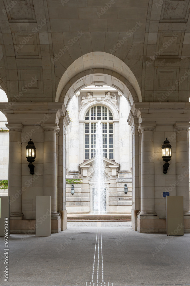 Fototapeta premium A large archway with a fountain in the middle. The archway is made of stone and the fountain is white