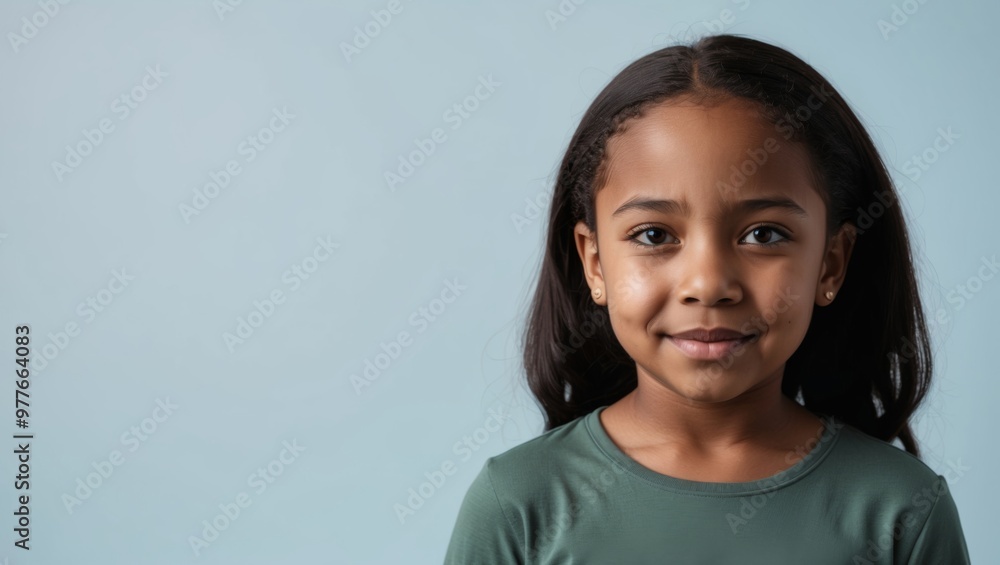 A young girl smiles gently against a blue background A young girl smiles gently against a blue background