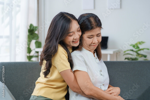 Daughter consoling her distraught mother on the couch. Demonstrating compassion and solidarity during a challenging period