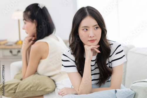 Two angry female friends sitting separately on sofa after having a big fight