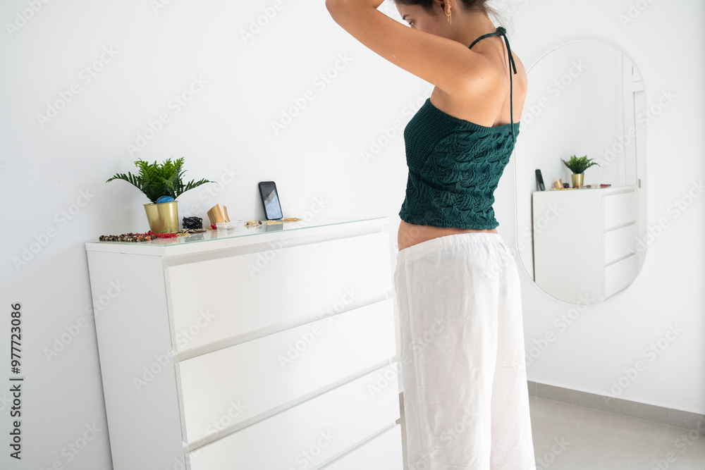 A young teenager prepares her hairstyle in front of her smartphone while making a story or a reel for social media networks. white day room and casual clothes. Teenage digital lifestyle concept A young teenager prepares her hairstyle in front of her smartphone while making a story or a reel for social media networks. white day room and casual clothes. Teenage digital lifestyle concept