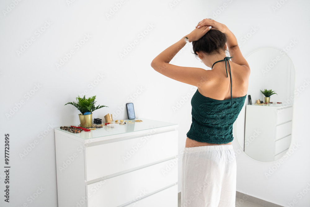 A young teenager prepares herself ion a mirror in front of her smartphone while making a story or a reel for social media networks. white day room and casual clothes. Teenage digital lifestyle concept A young teenager prepares herself ion a mirror in front of her smartphone while making a story or a reel for social media networks. white day room and casual clothes. Teenage digital lifestyle concept