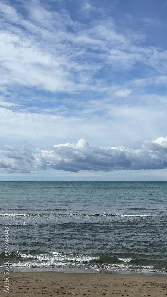 Sea waves on the sand bach in cloudy weather, vertical video. Sea waves on the sand bach in cloudy weather, vertical video.