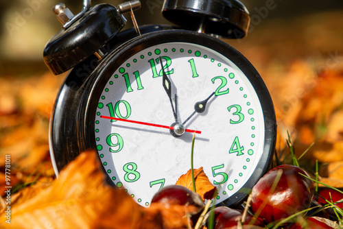 Symbolbild Zeitumstellung, Herbst: Ein Wecker zwischen Herbstlaub photo