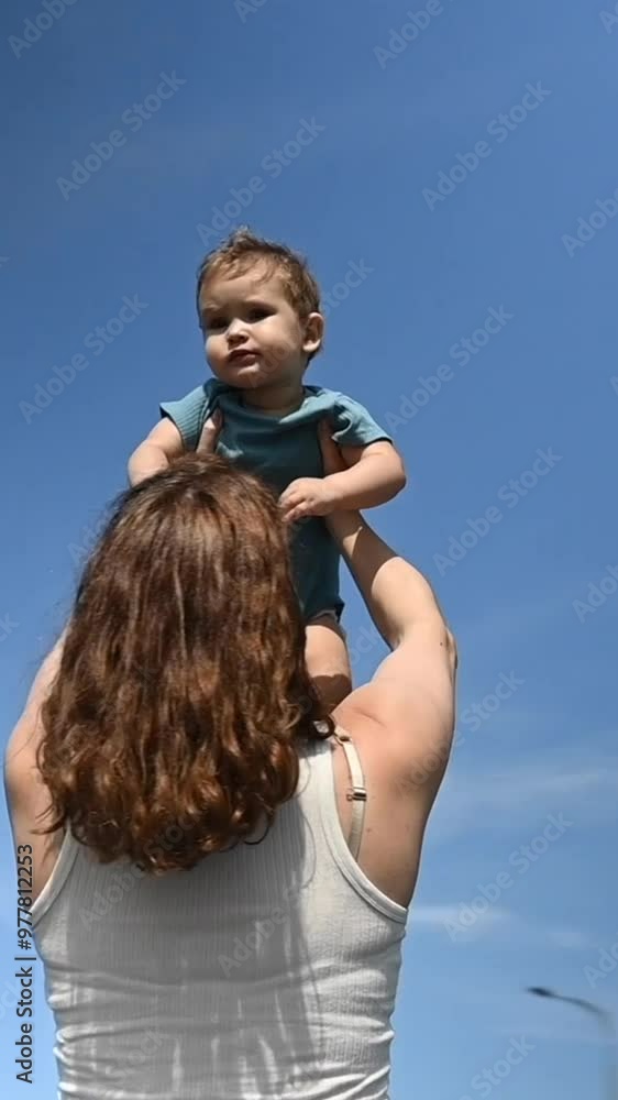 Caucasian woman holds her one-year-old son above her head. 360 degree vertical video. Caucasian woman holds her one-year-old son above her head. 360 degree vertical video.