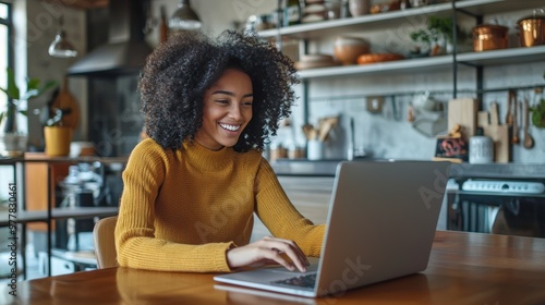 Cheerful Woman Working on Laptop in Modern Cozy Kitchen for Remote Work or Video Call Setup