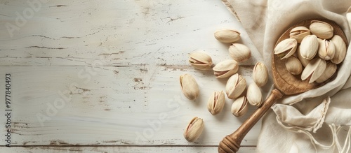 Close up of pistachios on a white wooden surface along with a spoon Selective focus Copy space