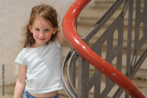 Little cute girl walking on stairs holding handrail. Children's exploration concept