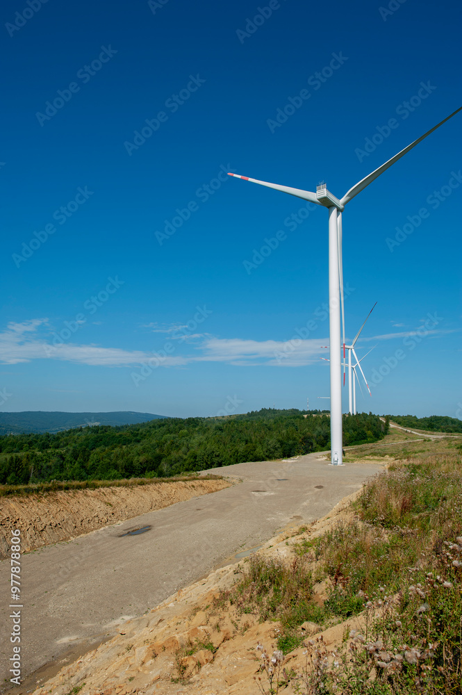The blades of a wind farm rotate against the sky. The concept of electricity production from renewable sources. The blades of a wind farm rotate against the sky. The concept of electricity production from renewable sources.