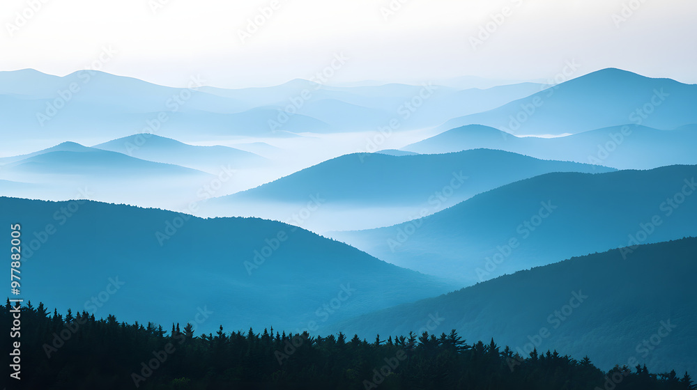 A misty mountain ridge with layers of peaks fading into the distance covered in early morning fog. A misty mountain ridge with layers of peaks fading into the distance covered in early morning fog.