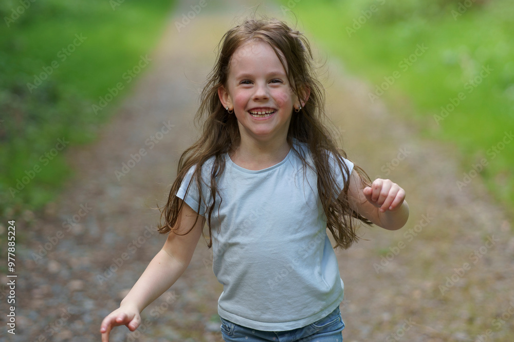 Obraz premium Little beautiful girl on the background of the road in the park. Happy childhood concept outdoors