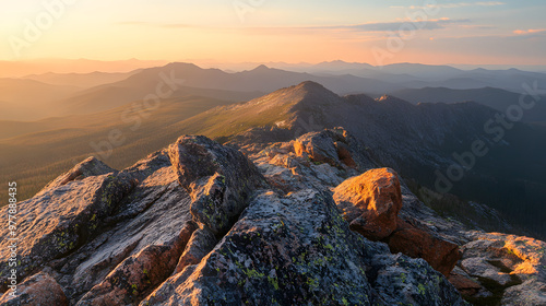 A rocky mountain summit with panoramic views of distant ranges bathed in soft golden light at sunset. photo