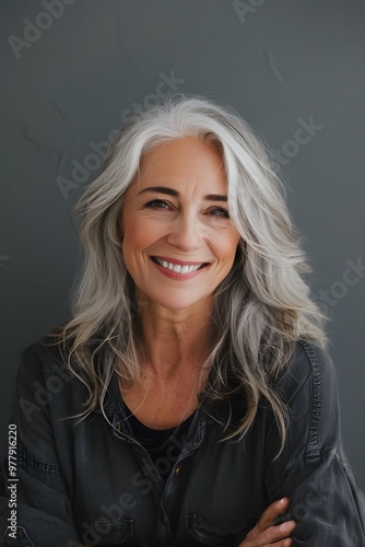 Radiant senior woman with silver hair smiling on a gray background