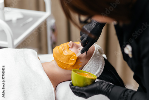 A young woman receives a revitalizing alginate face mask from a skilled cosmetologist in a sleek, modern beauty clinic. Perfect for promoting premium skincare treatments in your ads photo