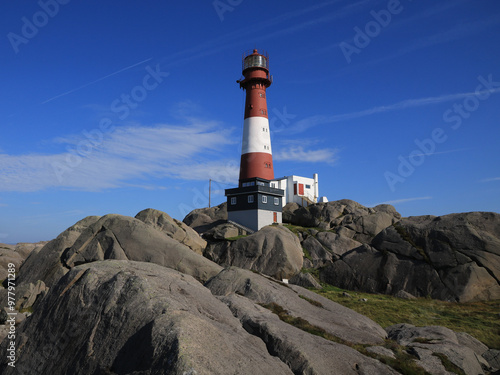 Red white Eigerøy Lighthouse and anorthosite rock formations, Norway. photo