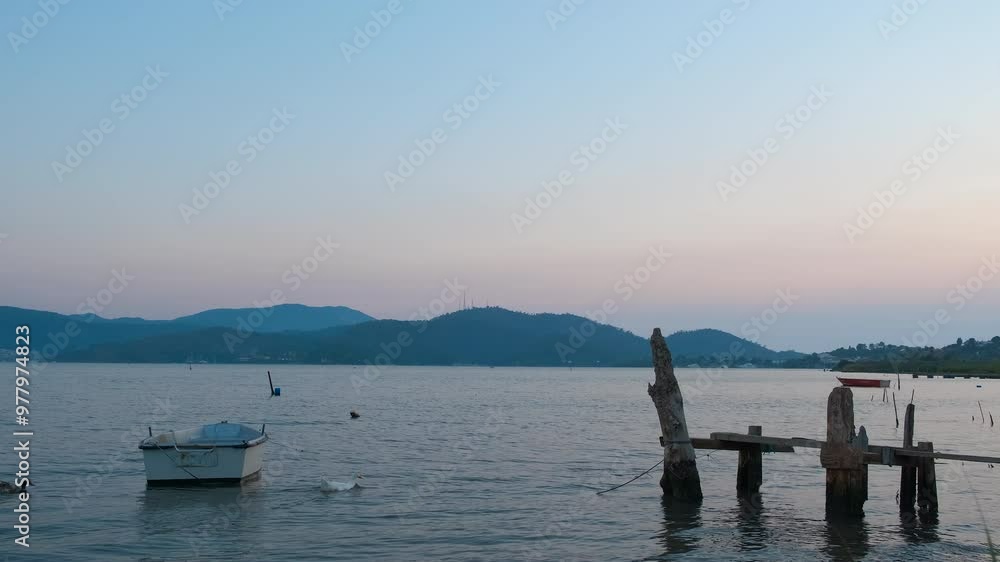 Boat by bank during morning nature. A view of small boat moored by the handmade pier against pink clouds in the morning. Boat by bank during morning nature. A view of small boat moored by the handmade pier against pink clouds in the morning.