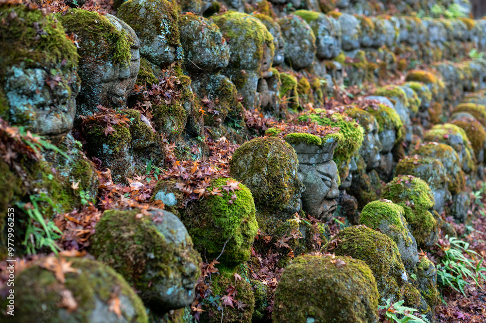 Moss-covered stone statues with autumn leaves in a peaceful setting Moss-covered stone statues with autumn leaves in a peaceful setting