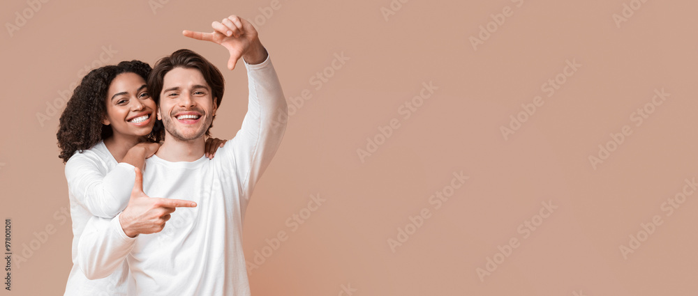 Capturing happy moments. Romantic interracial couple making frame with hands and embracing over yellow background, copy space Capturing happy moments. Romantic interracial couple making frame with hands and embracing over yellow background, copy space