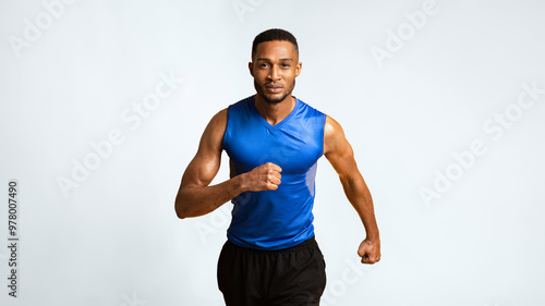 Running Competition. Confident black sportsman running, looking at camera, yellow background. Panorama, copyspace