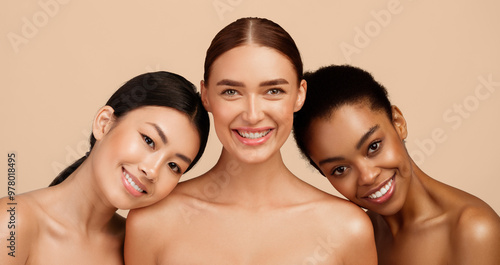 Three Joyful Girls Posing Wrapped In White Towels Standing On Gray Studio Background After Shower. Spa And Body Care Concept