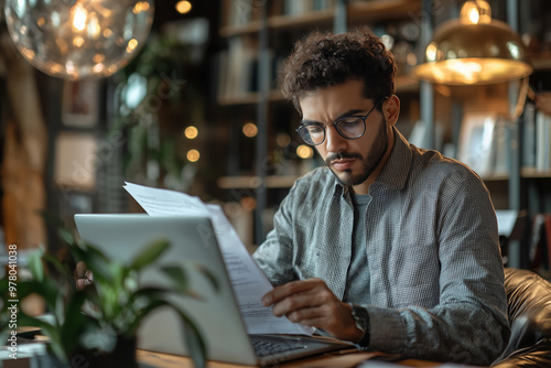 Focused Man Working on Laptop and Paperwork in Office