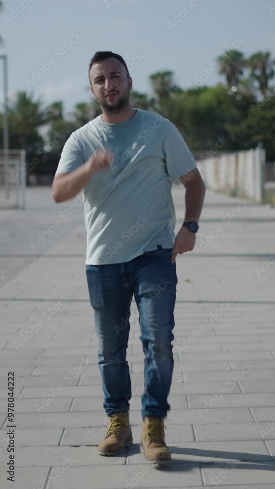 Young Caucasian boy walking in front of camera on the concrete walkway between palm trees insulting threatening talking pointing and gesturing Young Caucasian boy walking in front of camera on the concrete walkway between palm trees insulting threatening talking pointing and gesturing