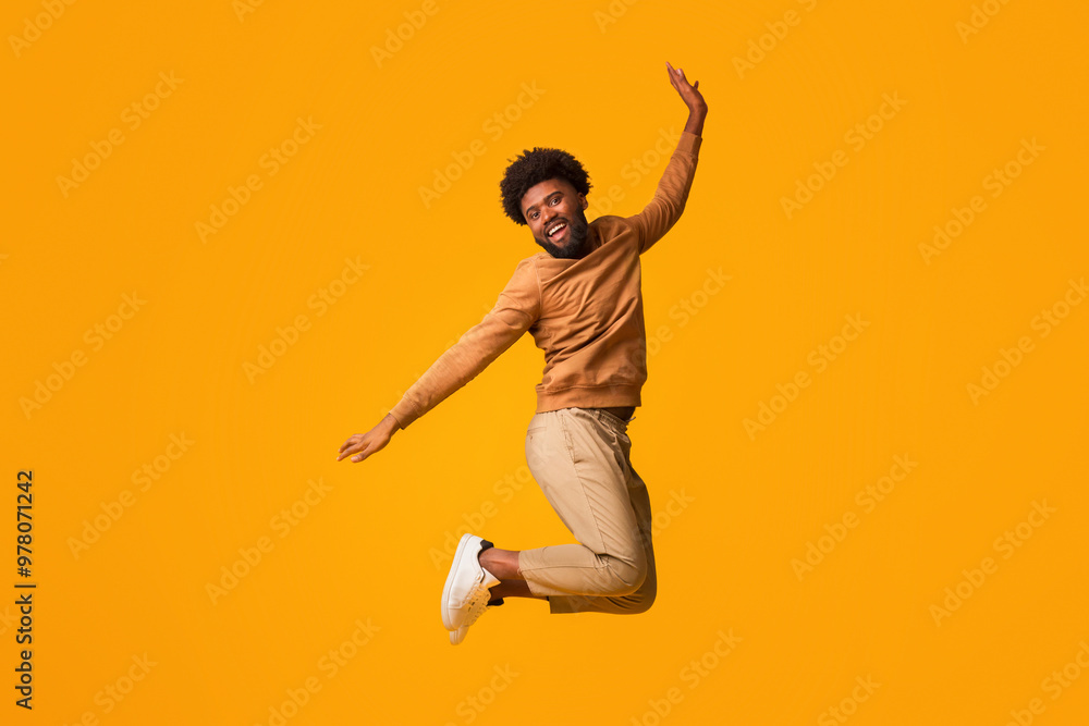 Feeling good. Positive afro man jumping up over orange studio background Feeling good. Positive afro man jumping up over orange studio background