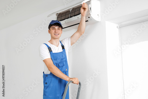 Male worker repairing air conditioner in room