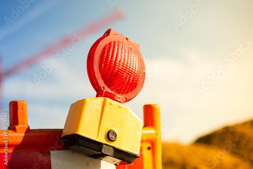 Yellow warning light on a construction site. Crane in background. Day, outside, sun.
