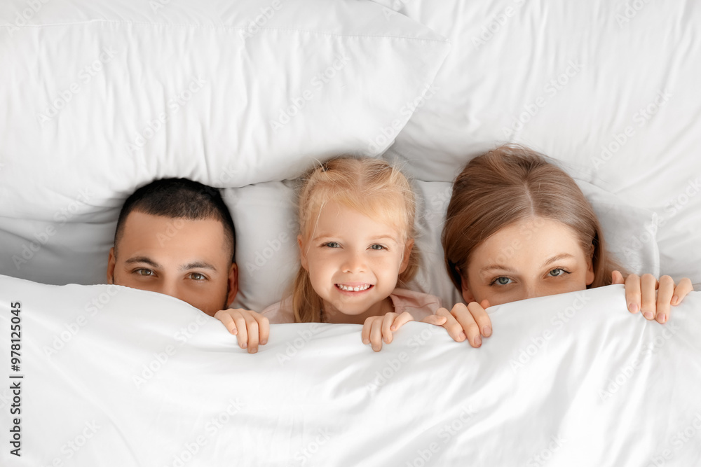 Parents with their little daughter lying under blanket on bed, top view Parents with their little daughter lying under blanket on bed, top view